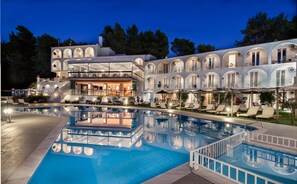 Un hotel con una piscina grande, varios balcones y zonas de estar al aire libre.