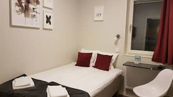 A hotel room with a bed, a chair, and a window.