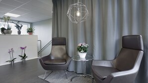 A modern office space with two leather chairs, a glass table with a flower vase, and a geometric pendant light. - Hotell Eken (Kållered)
