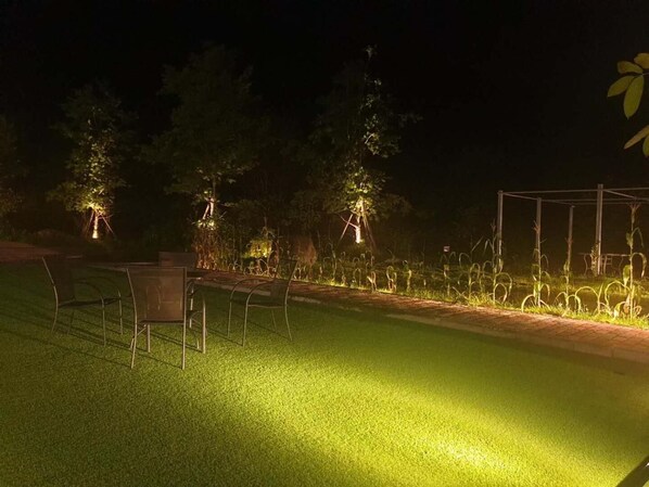 A nighttime outdoor area with artificial lighting, a paved path, and a metal structure.