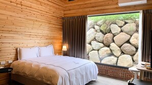 A wooden-paneled room with a bed, a window with a stone wall view, and an air conditioning unit. - BlackJazz Inn (Puli)