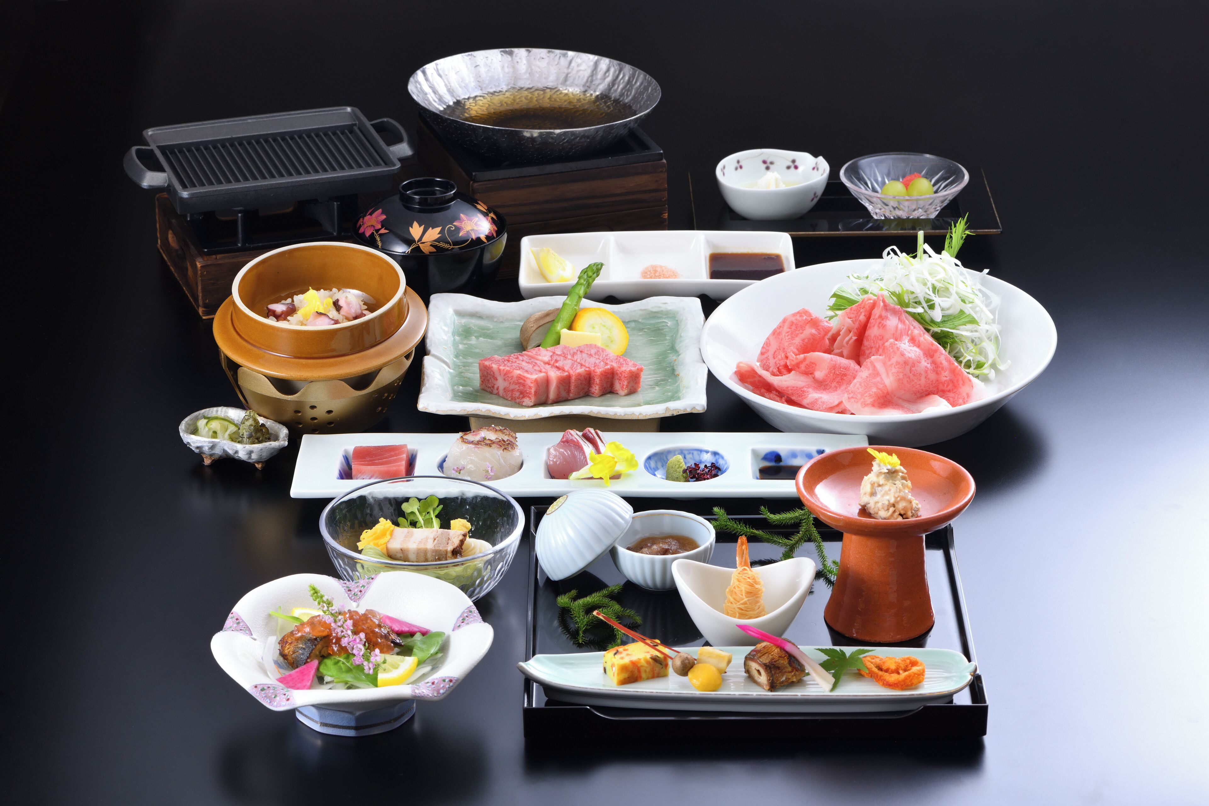 A variety of dishes and food items arranged on a table, including plates of meat, vegetables, and other delicacies.