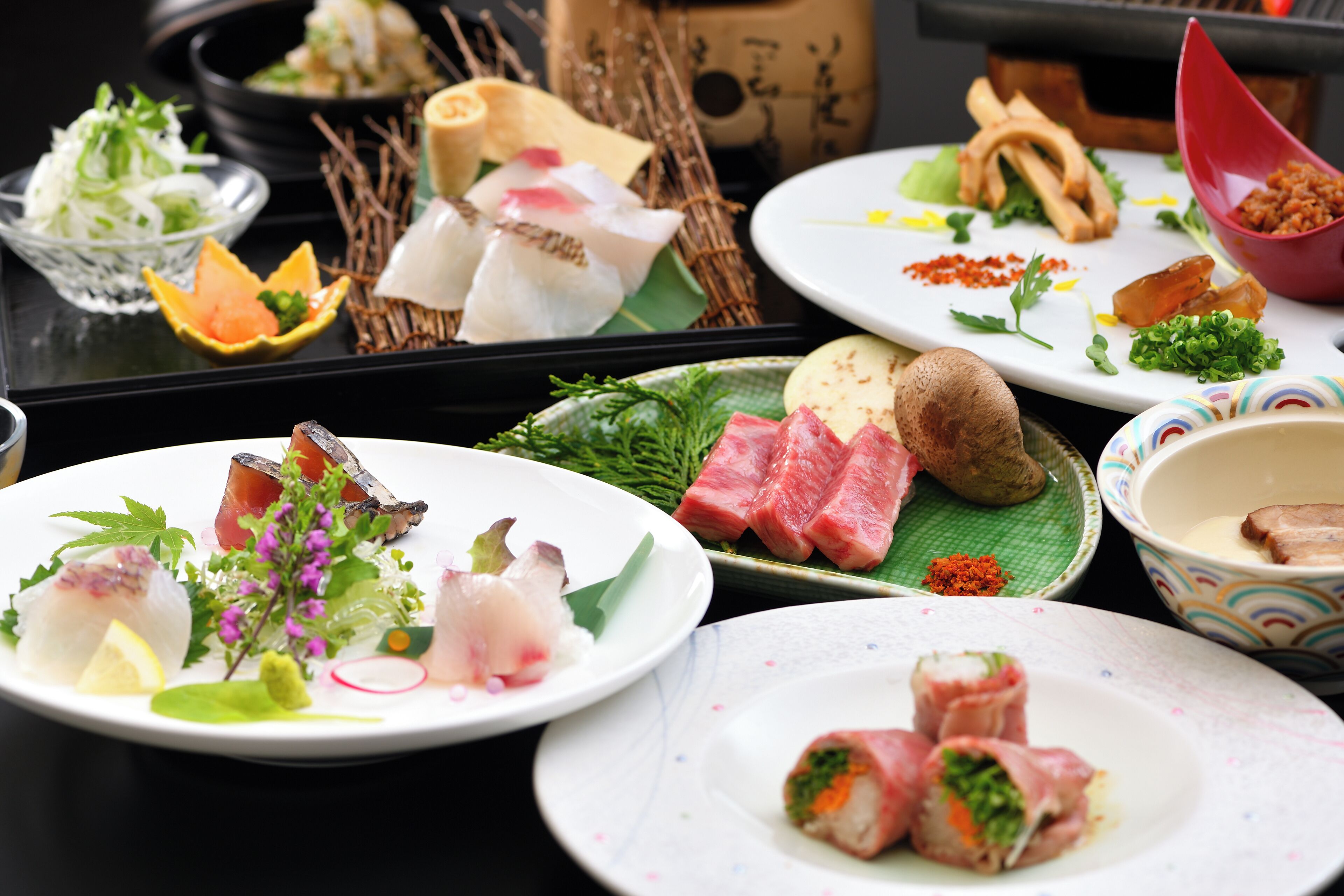 A variety of dishes on a table, including sashimi, sushi, and other Asian cuisine.