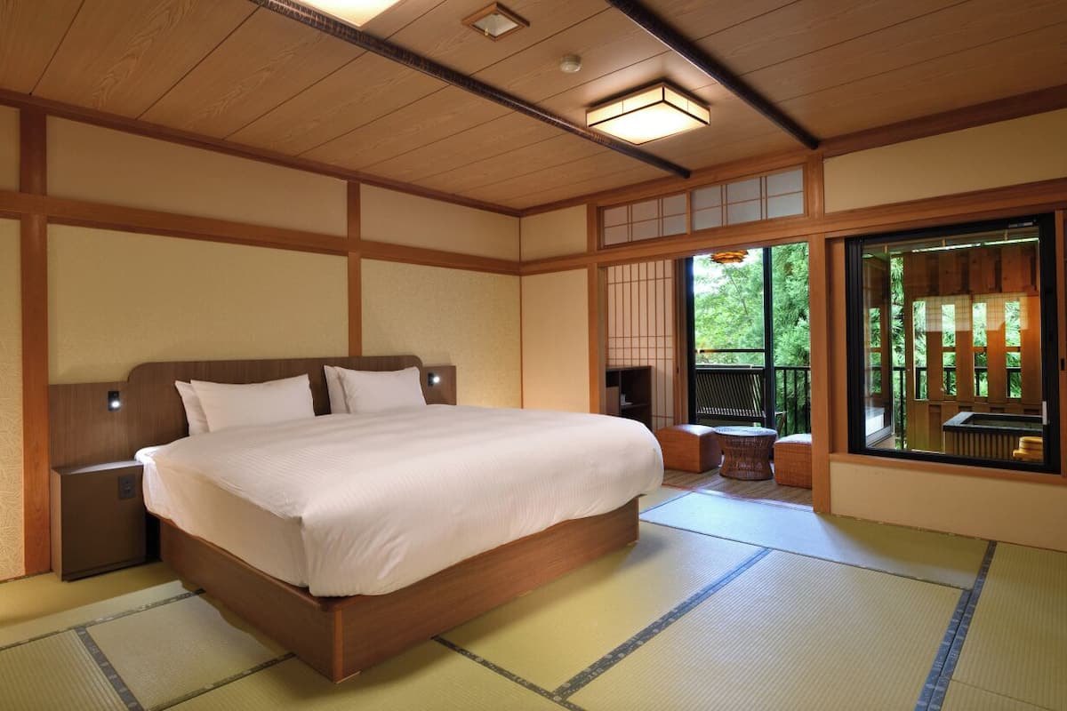 A traditional Japanese-style bedroom with tatami flooring, a wooden bed, and a sliding door leading to a balcony.