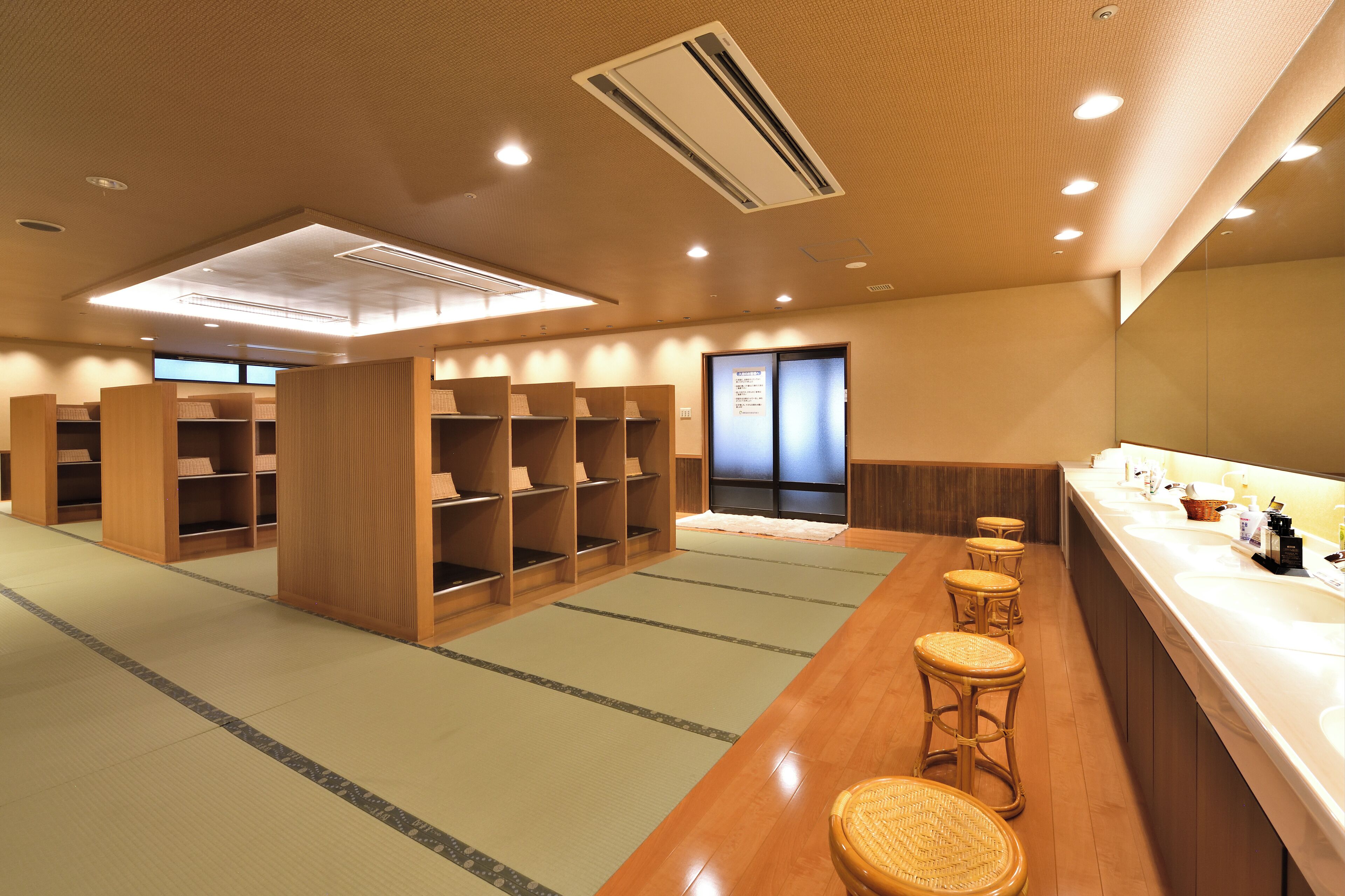 Habitación de hotel con muebles de madera, una mesada con lavamanos y suelo de esteras de tatami.