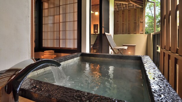 A traditional Japanese onsen with a stone basin, wooden sliding doors, and a view of the surrounding architecture. - Yunogo Onsen HOTEL YUNOMORI (Mimasaka)