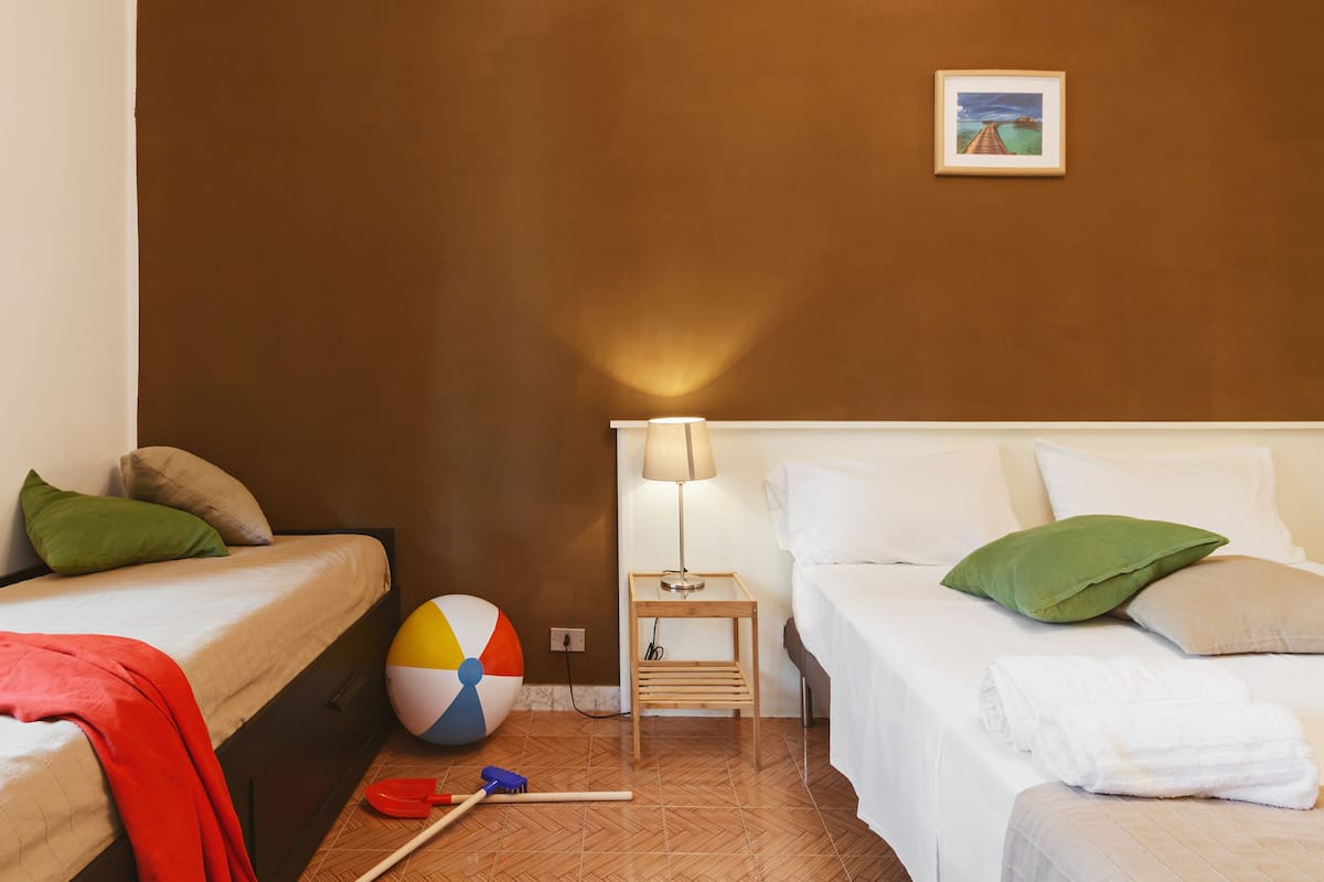 Habitación de hotel con dos camas, una mesita con una lámpara, una pelota de playa y un cuadro en la pared.