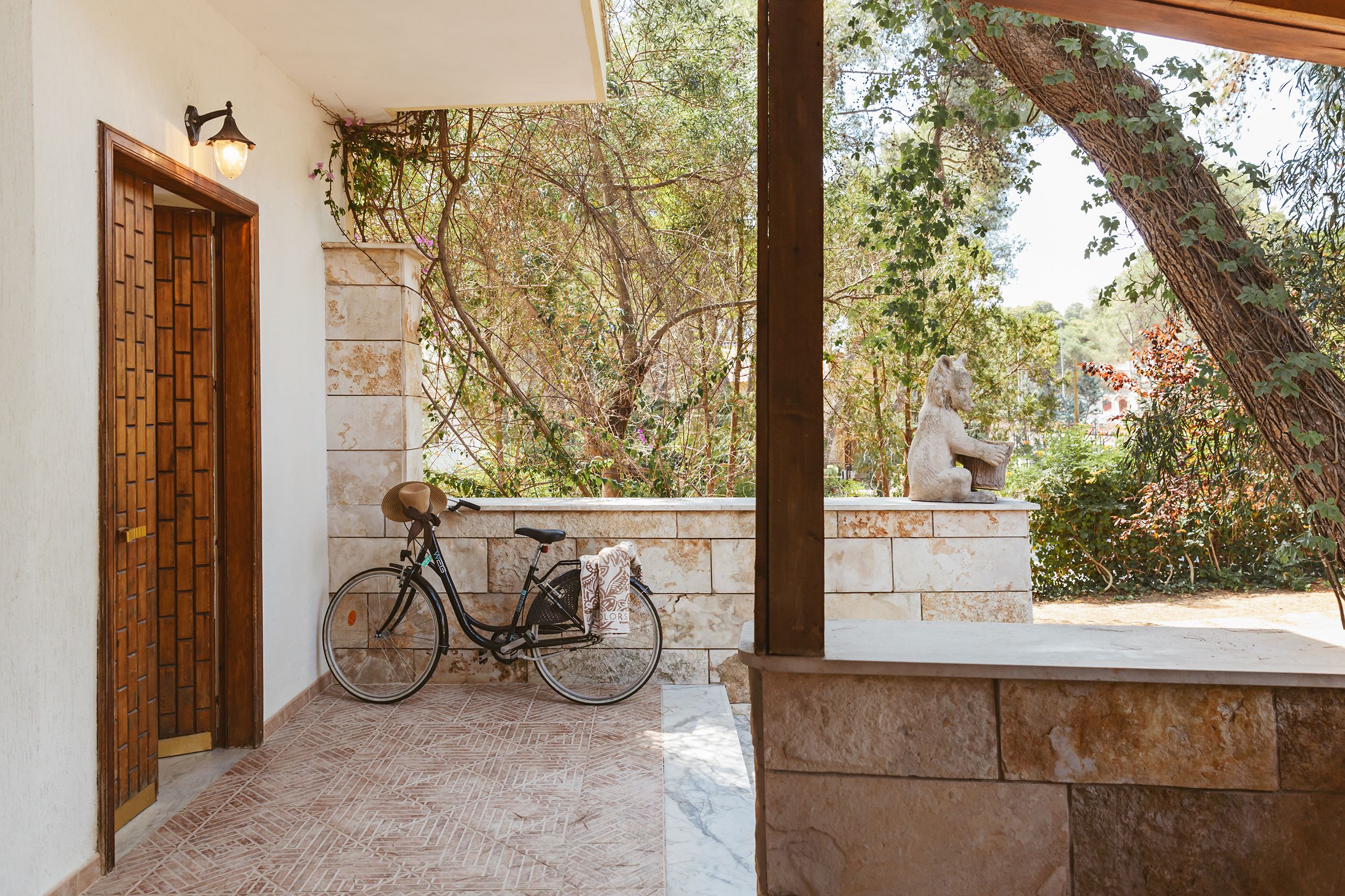 A wooden door, a bicycle, and a statue in a garden setting.