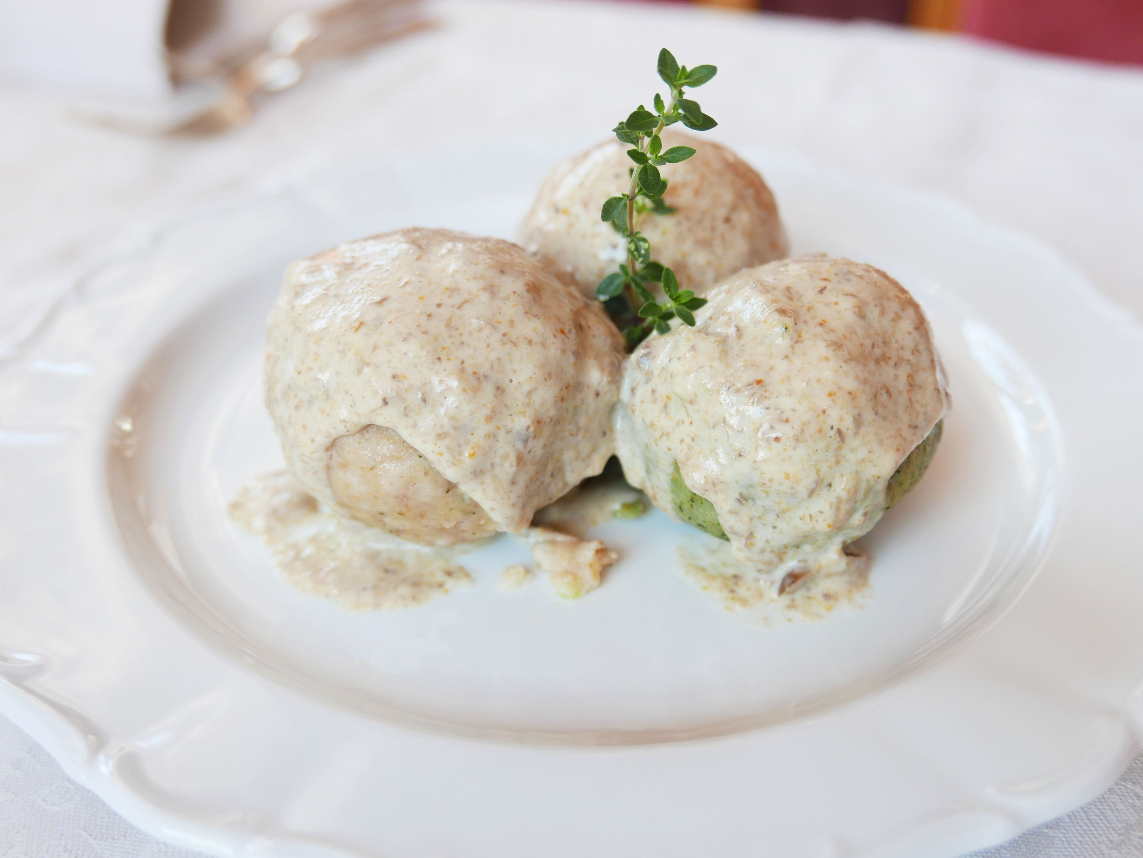 Tre ravioli con salsa cremosa su un piatto bianco.