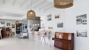 Une galerie d’art avec des tableaux accrochés aux murs, des meubles en bois et des paniers suspendus.