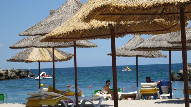 A beach with thatched umbrellas and lounge chairs. - Semiramis Hotel (Saturn)