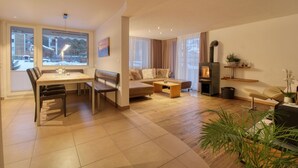 A modern living room with a dining area, a sofa set, a coffee table, and a fireplace. - Matterhorngruss Apartments (Zermatt)