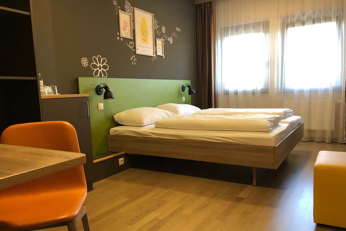A hotel room with a bed, a desk, and a chair.