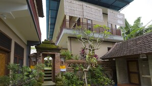 A two-story building with a balcony, surrounded by lush greenery and a small garden. - Murni's Villa Ligondi (Ubud)
