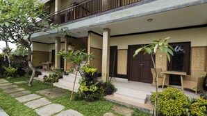 A two-story building with a covered porch, stone steps, and outdoor seating. - Murni's Villa Ligondi (Ubud)