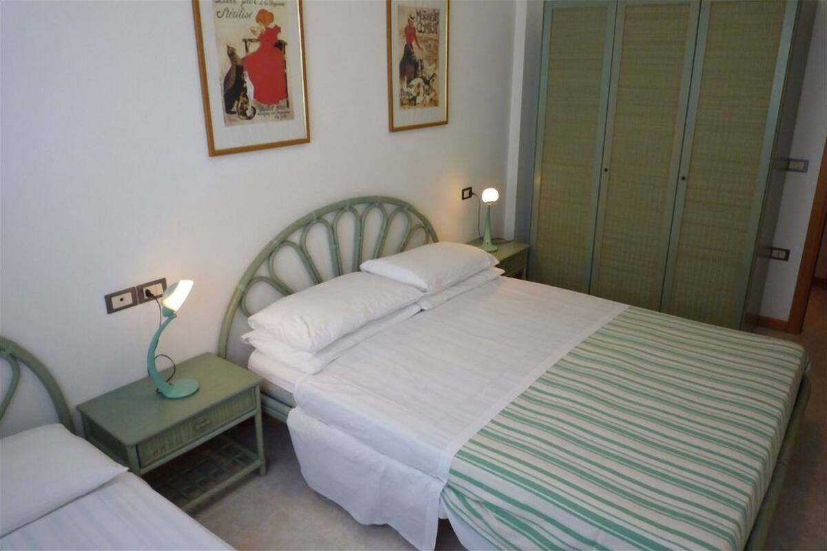 Un dormitorio con una cama individual, una mesita de noche con lámpara y dos carteles enmarcados en la pared.