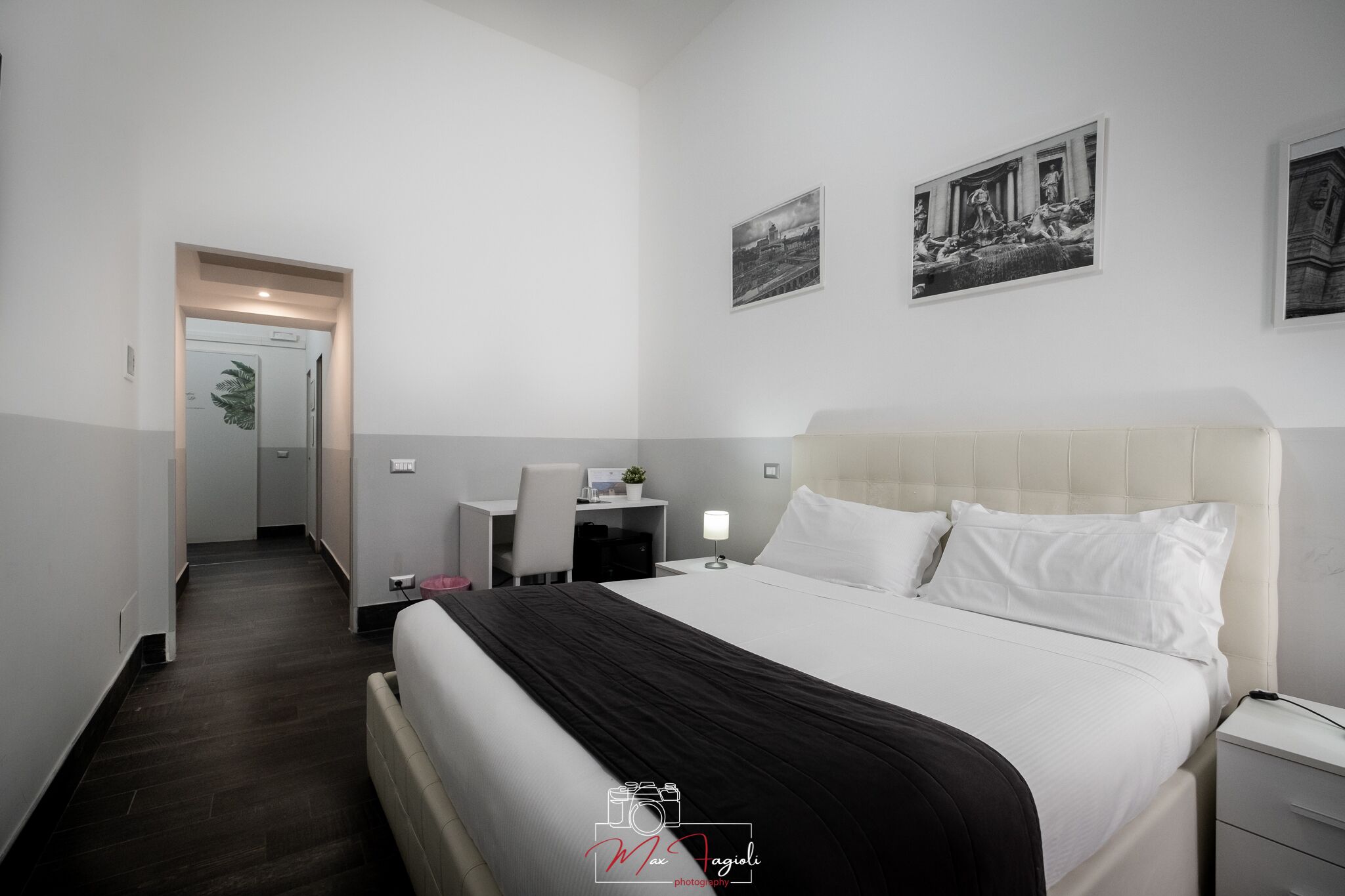 Ein Hotelzimmer mit einem großen Bett, einem Schreibtisch und zwei gerahmten Bildern an der Wand.