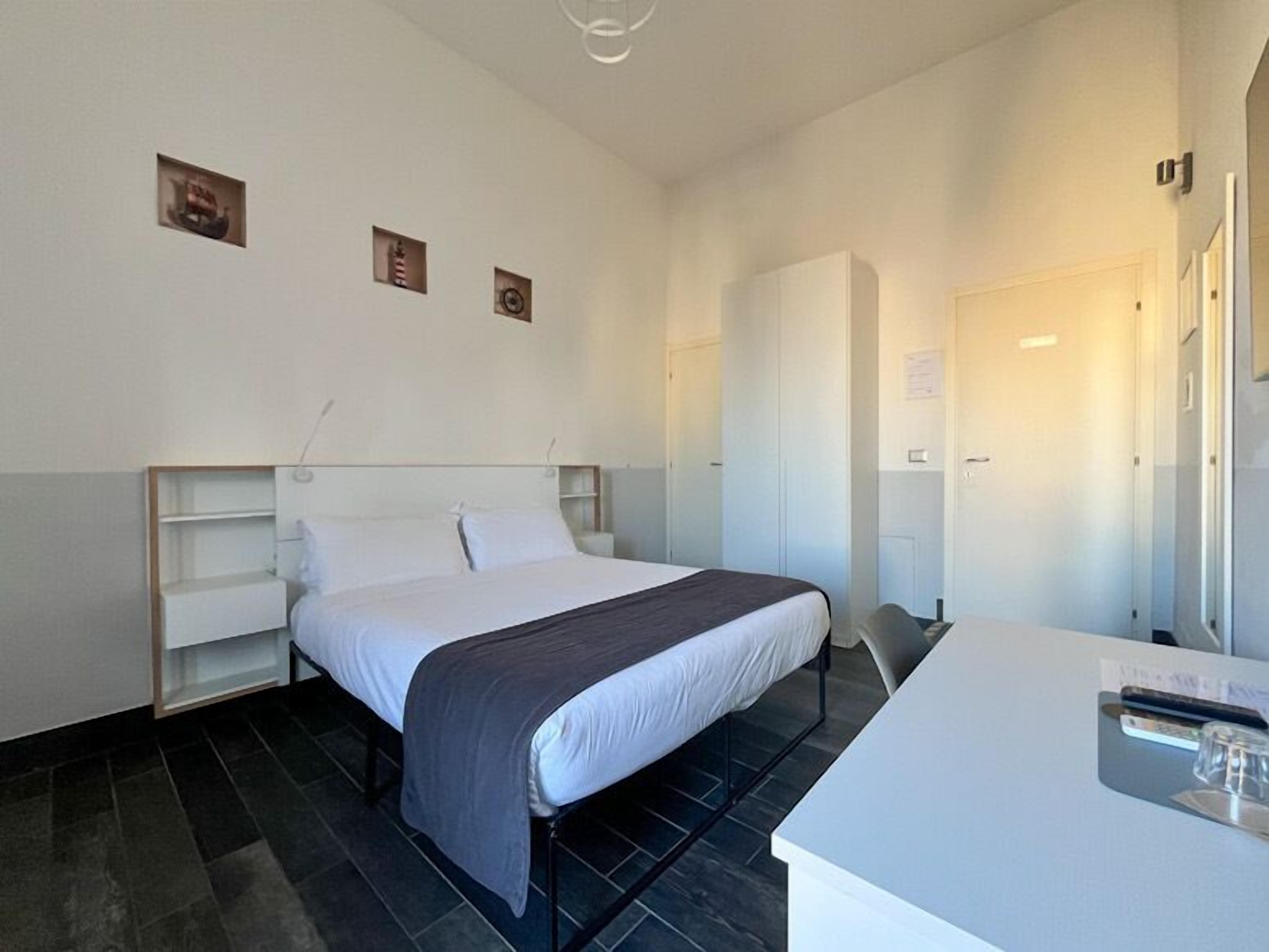 A hotel room with a bed, a desk, and a wardrobe.