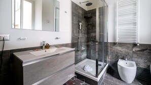 A modern bathroom with a glass-enclosed shower, a bidet, and a large mirror. - Arch Rome Suites (Rome)