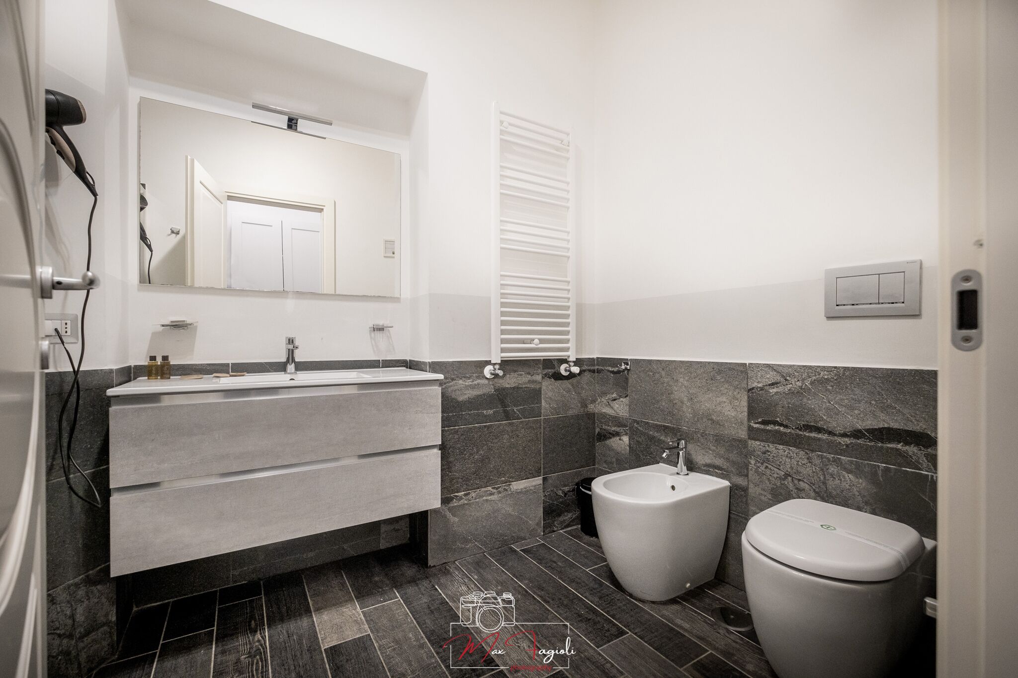 Ein modernes Badezimmer mit einem grauen Waschtisch, einem Bidet und einer Toilette.
