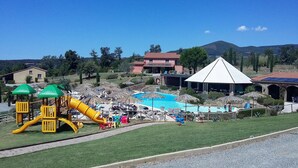 A resort with a pool, a playground, and a mountain backdrop.