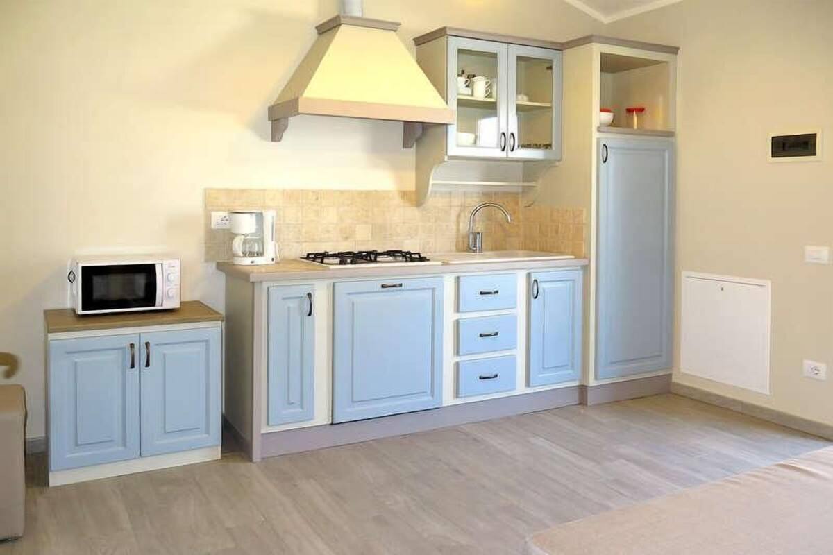 Une cuisine de taille réduite équipée d’un four à micro-ondes, d’une cuisinière et de placards.