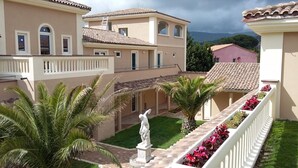 A courtyard with a statue, palm trees, and a staircase with flower boxes.