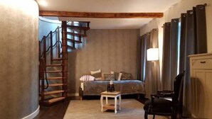 Quarto com cama, uma mesinha, cadeira, luminária, escada e guarda-roupa.