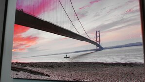 Vista de un puente sobre el agua, con un barco a lo lejos.