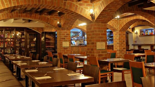 Un restaurante con arcos de ladrillo, mesas y sillas de madera.