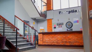 Un área de recepción con un reloj, una escalera y una pared de ladrillo.