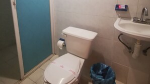 A bathroom with a toilet, sink, and a blue trash bin.