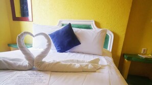 A neatly made bed with a heart-shaped towel arrangement, a blue pillow, and a white pillow.