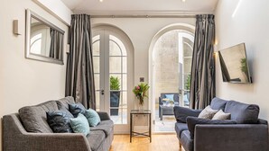 A modern living room with two sofas, a small table, and a large window with curtains. - Bath Circle (Bath)