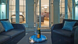 A cozy seating area with two sofas and a table, a bottle of champagne, and a candle. - Bath Circle (Bath)
