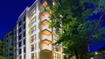 A multi-story building with balconies, large windows, and a well-lit facade.
