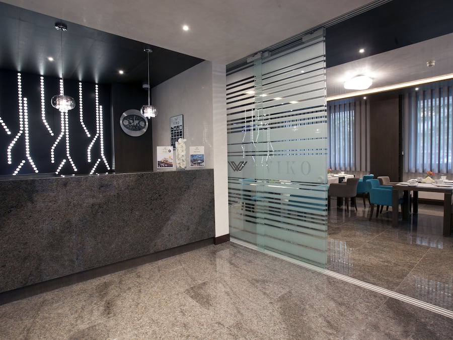 A modern reception area with a marble counter, decorative light fixtures, and a glass partition with the name "WILCO" on it.