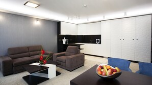Una sala moderna con sofá, sillón, mesa de centro y frutero.