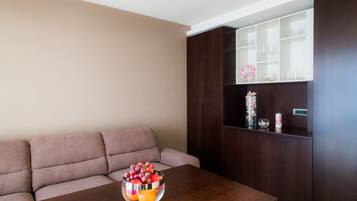 A living room with a wooden coffee table, a beige sofa, and a dark wooden cabinet with glassware.