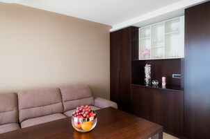 A living room with a wooden coffee table, a beige sofa, and a dark wooden cabinet with glassware.