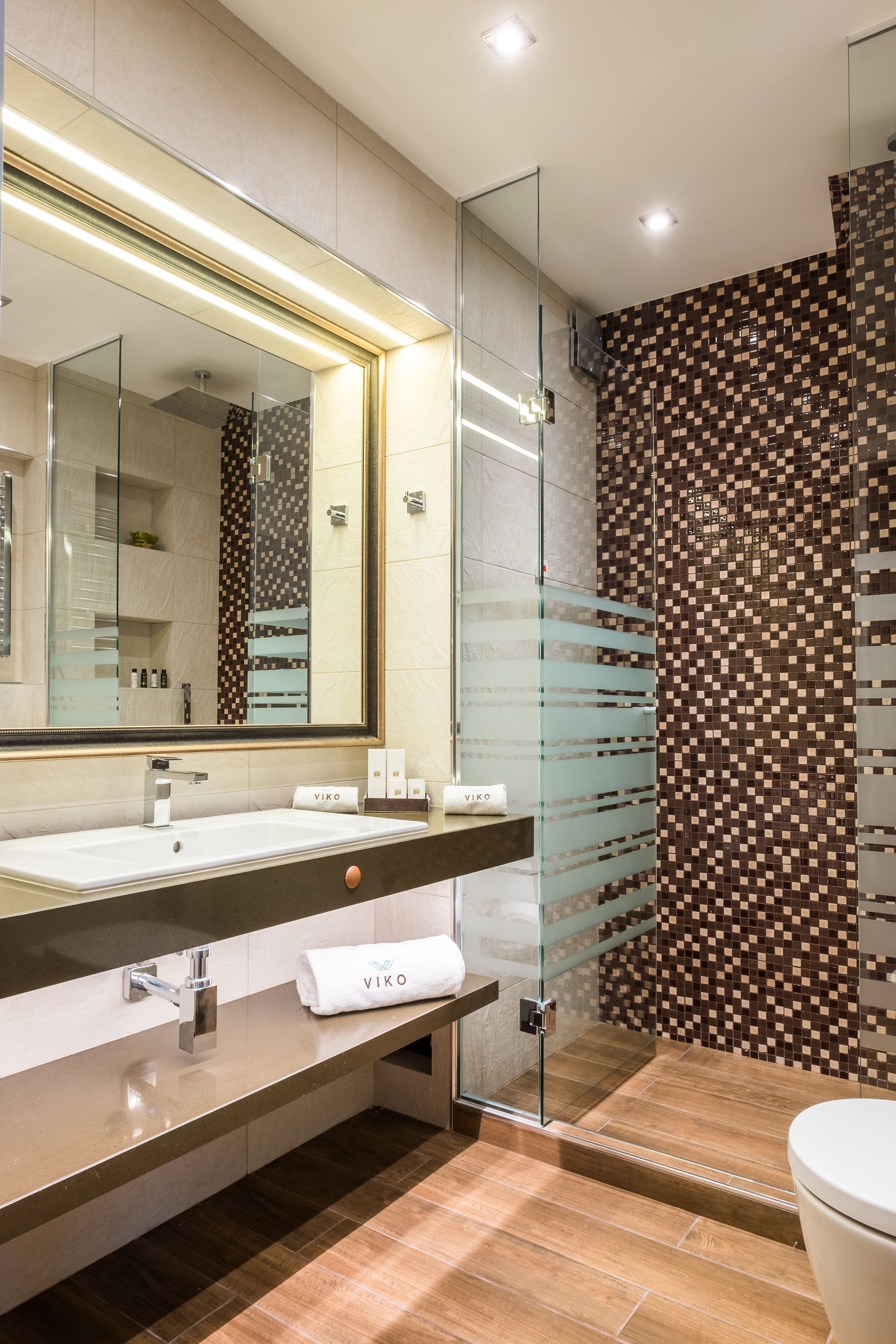 A modern bathroom with a large mirror, a sink, and a glass shower enclosure.