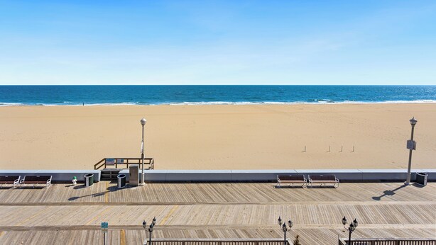 A wooden boardwalk leading to a beach with a clear view of the ocean. - Americana Motor Inn (Ocean City)