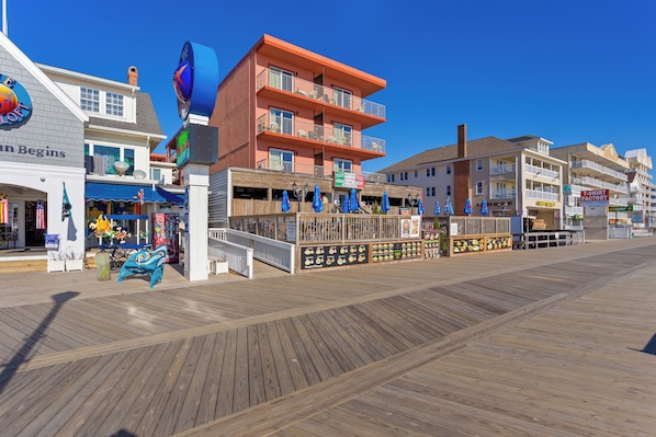 A boardwalk with shops and restaurants, wooden walkways, and a clear blue sky. - Americana Motor Inn (Ocean City)