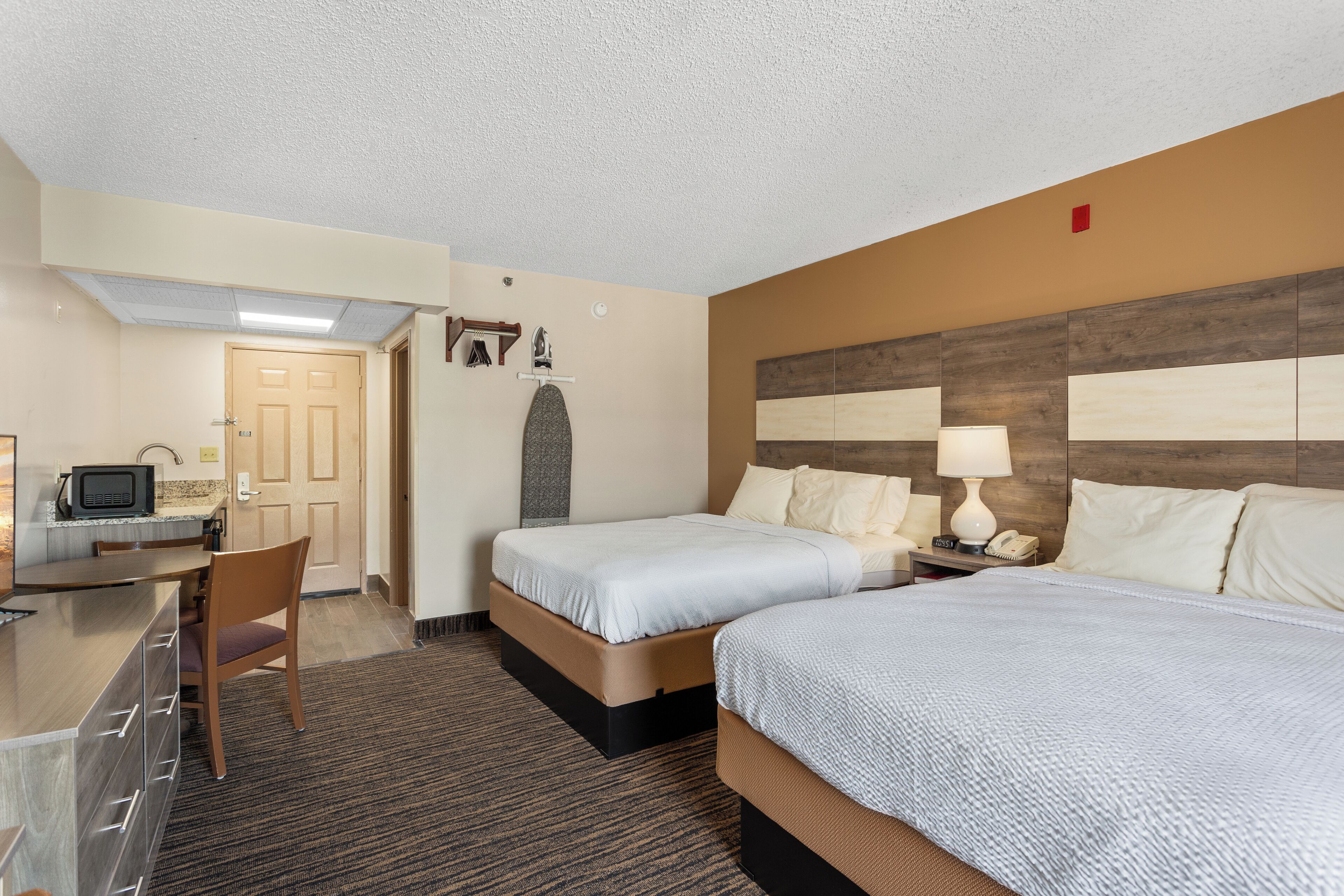 Une chambre d’hôtel avec deux lits, un bureau, une chaise, un four à micro-ondes et un téléviseur.