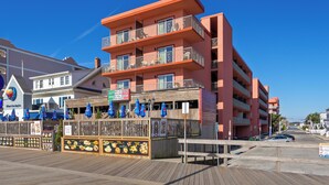 A multi-story hotel with balconies, a boardwalk, and a restaurant with outdoor seating. - Americana Motor Inn (Ocean City)