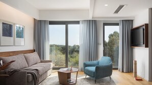 A modern living room with a sofa, a blue armchair, a coffee table, and a TV on a wall. - Hotel & Restaurant Milan (Pula)