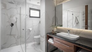Un baño moderno con ducha de vidrio, inodoro y tocador con lavamanos y espejo.