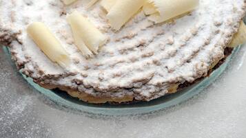 A round cake with powdered sugar and rolled wafer cookies on top.