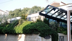 A modern building with a glass facade, a stone wall with greenery, and a sign indicating a hotel and restaurant. - Hotel & Restaurant Milan (Pula)