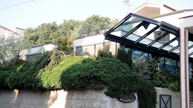 A modern building with a glass facade, a stone wall with greenery, and a sign indicating a hotel and restaurant. - Hotel & Restaurant Milan (Pula)